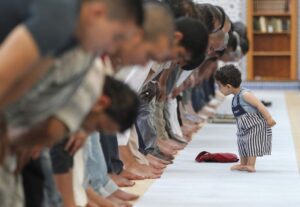 Muslim praying Namaz with 1st Surah in the Quran..kid is runing around